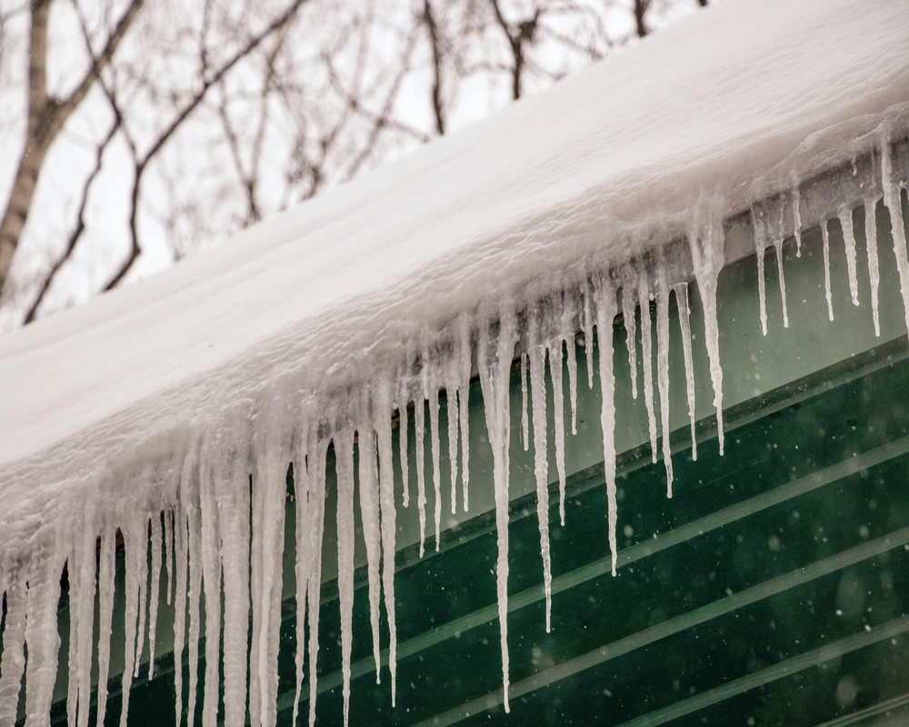 ice dams forming on roof edge in Edmonton with icicles and winter buildup